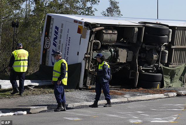 Police inspect an overturned bus near the town of Greta following a crash in the Hunter Valley that killed 10 people.