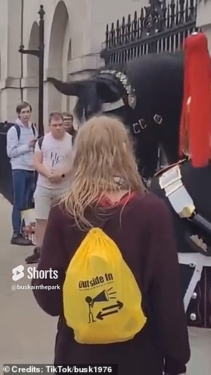 The woman, who was holding a blue can of Pringles, was seen standing very close to one of the mounted guards, while other bystanders gave the guards more space by standing further away.