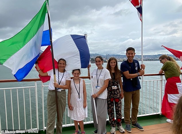 Simon and his family raising the flags of Great Britain, France and Sierra Leone