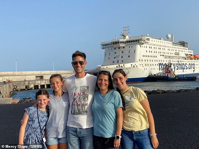 The family photographed smiling together for a family photo in front of the medical ship