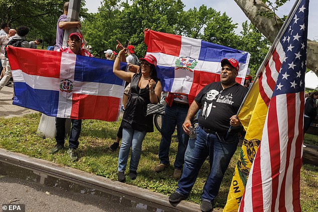 People with flags of the Dominican Republic and the United States sing while waiting in line to attend a rally by former US President Donald Trump in Crotona Park, in the New York borough of the Bronx.