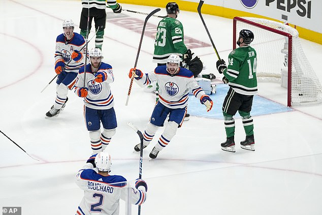 McDavid, center left, gestures toward fellow defenseman Evan Bouchard after the assist