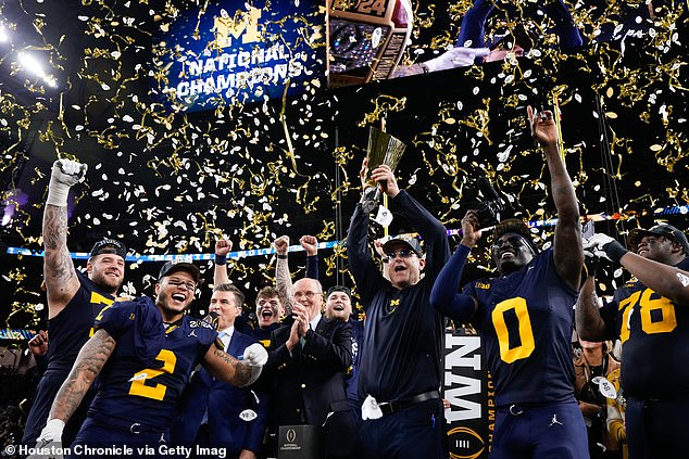 Michigan Wolverines head coach Jim Harbaugh hoists the championship trophy