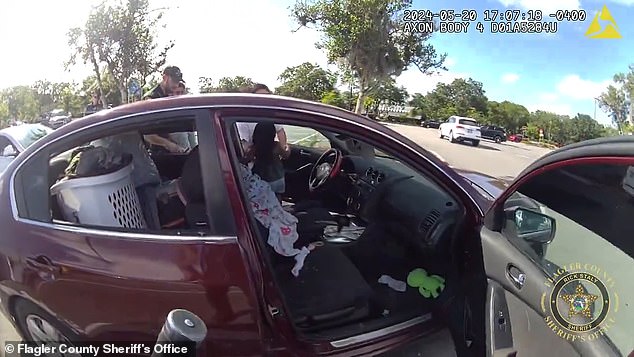 The two adults who were found standing outside the car when officers arrived said the boy was inside the Nissan Altima for 10 minutes. (in the photo: the girl is taken out of the driver's seat)