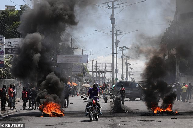 Motorists drive past a burning barricade during a protest following an escalation of violence, in Port-au-Prince, Haiti, on March 7, 2024.