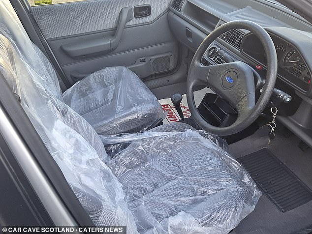 The interior appears to be unused, with the seat covers still in place to protect the cloth seats.