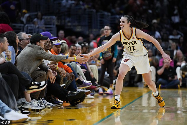 Indiana Fever guard Caitlin Clark greets Iowa teammate Ashton Kutcher after shooting a shot.