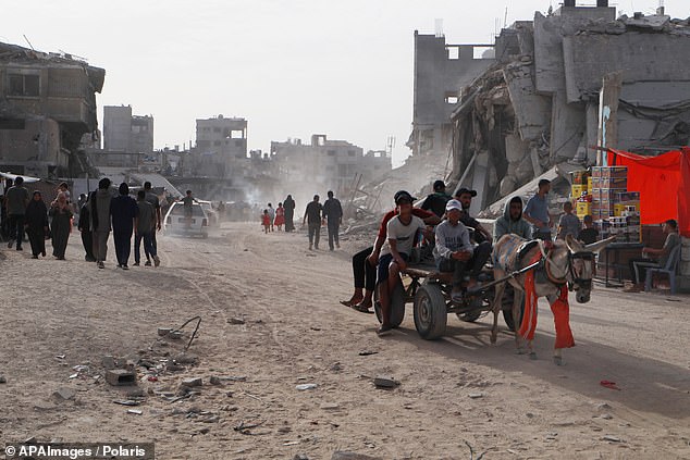 Displaced Palestinians walk through a devastated street in Khan Yunis, southern Gaza Strip, on May 24, 2024.