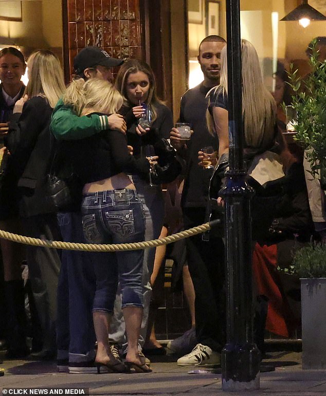 A friend put his arm around the star as she chatted with friends outside a bar.