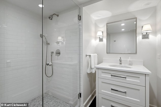 Pictured: A luxurious tiled bathroom with all white accents adds timeless feng shui to the space.