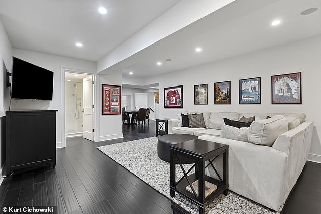 Pictured: The basement living room with modern furniture and sporty decor.