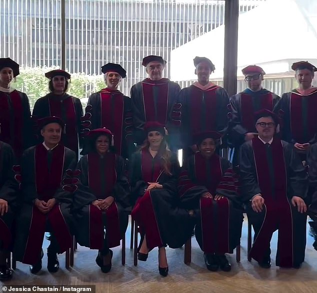 The video then shows Chastain joining other graduates and alumni as they pose together for a photo in front of a large window that allowed natural light to flow into the building.