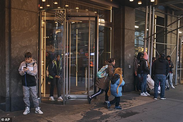 Migrant families walk to school in front of the Row Hotel that serves as a migrant shelter