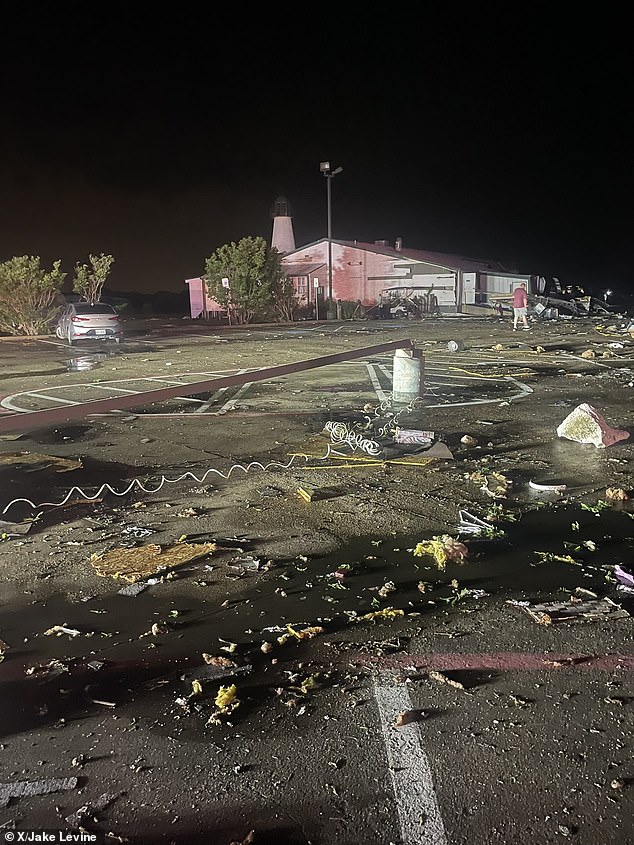 Debris is scattered in this parking lot and a man is seen wandering around the damage early Sunday morning.