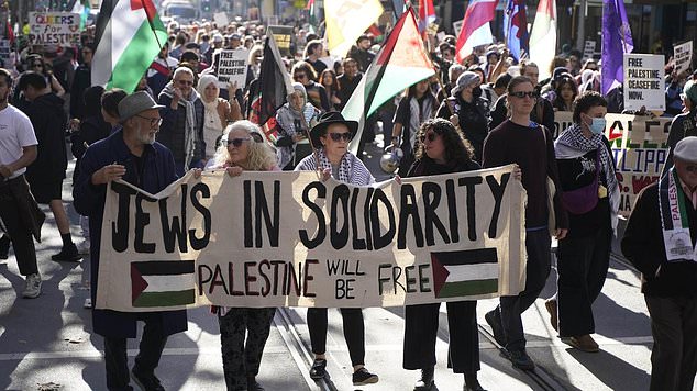 In the photo: Protesters carry a sign that says "Jews in solidarity: Palestine will be free'