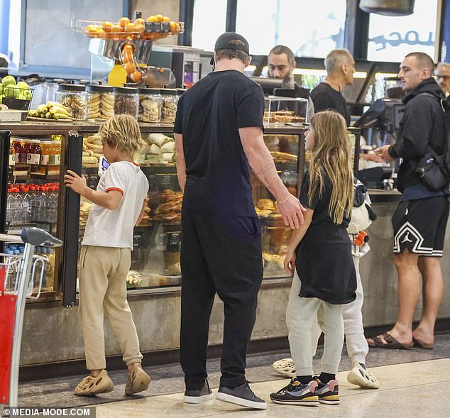 After approaching the busy counter, Chris was seen chatting with his children while looking at a cake in the window.