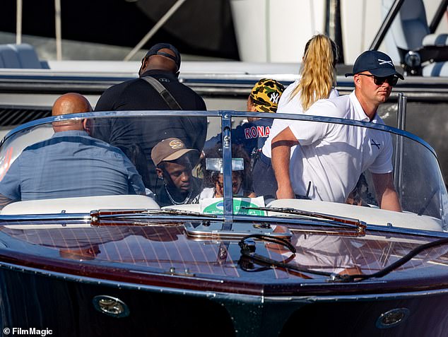 Travis and his daughter were seen sitting in the front of a sleek dark brown boat on the water in Monte Carlo.