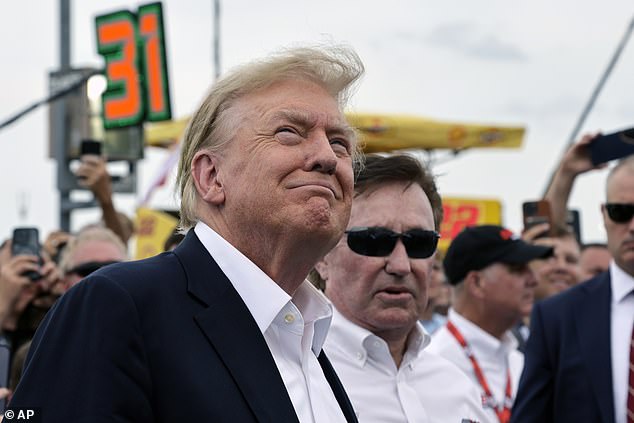 President Donald Trump smiles as a military plane flies overhead while attending the NASCAR Coca-Cola 600.