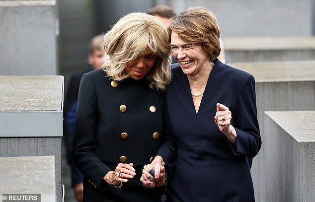 The First Lady of France and Brigitte Macron and the First Lady of Germany, Elke Buedenbender, holding hands as they walk past the memorial to the six million people murdered by Nazi Germany during World War II.