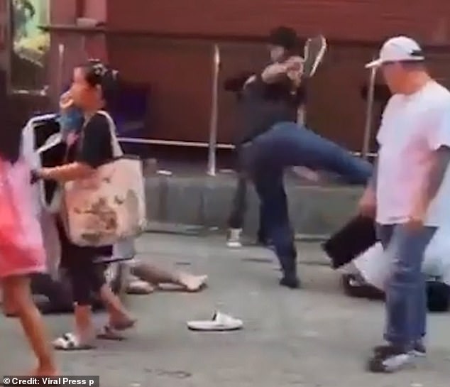 A goalkeeper throws a roundhouse kick at the tourist sitting on the cement.