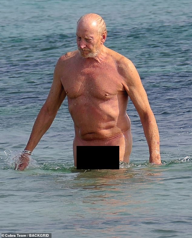 The father-of-three (pictured) proudly showed off his toned physique as he strolled along the beach before enjoying a dip in the sea.