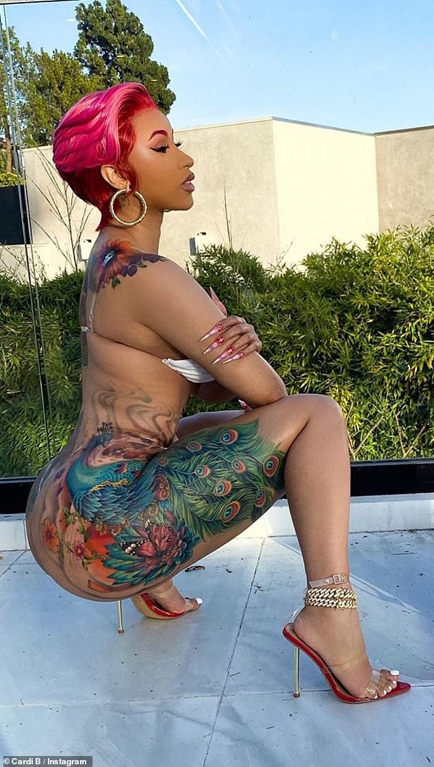 Rapper Cardi B showed off her elaborate, shiny thigh tattoos as she posed in a white bra.