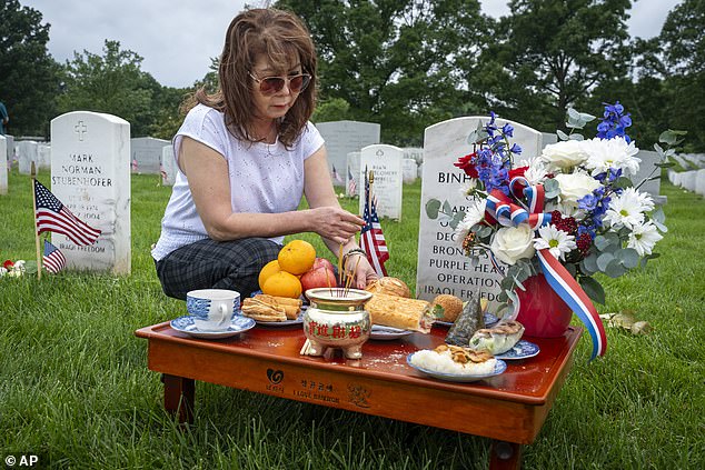 Kim Hoan Nguyen of Falls Church, Virginia, originally from Vietnam, places ritual offerings according to Vietnamese tradition at the grave of her son, Marine Corporal Binh N Le, who died serving in Iraq in 2004.