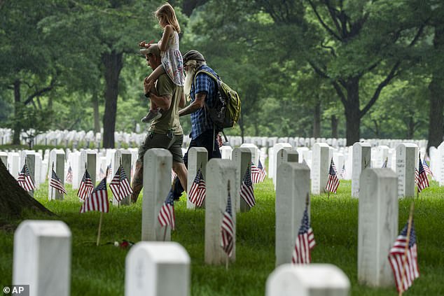 Two men and a girl walk among the headstones in Section 60 of Arlington National Cemetery.