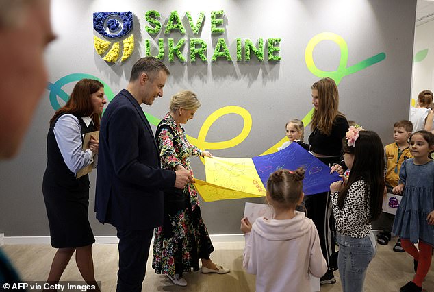 Sophie and her children look at a Ukrainian flag while visiting the Save Ukraine family center in the city of Irpin on April 29, 2024.