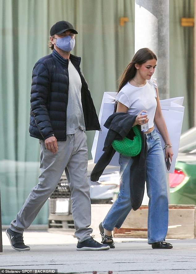 The teenager seemed happy as she walked down the sidewalk, alongside her family, with two large shopping bags on her shoulder.