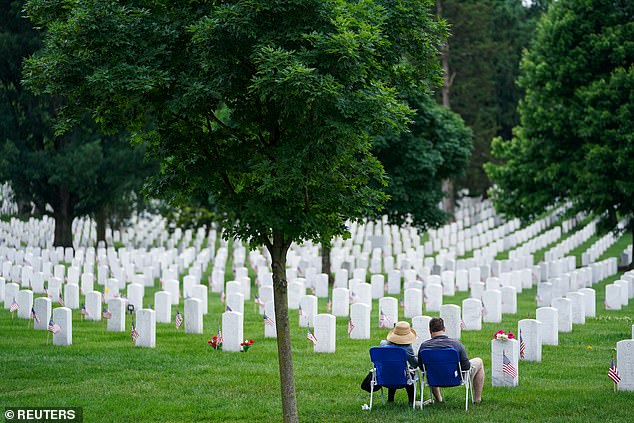 Visitors rest near headstones at Arlington National Cemetery on Memorial Day in Arlington, Virginia, USA, May 27, 2024