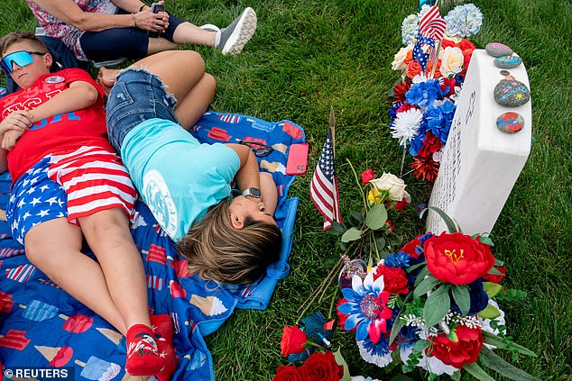 Sarah Schumann rests at the grave of her husband, Army Specialist Jordan Schumann, at Arlington National Cemetery on Memorial Day in Arlington, Virginia, U.S., May 27, 2024