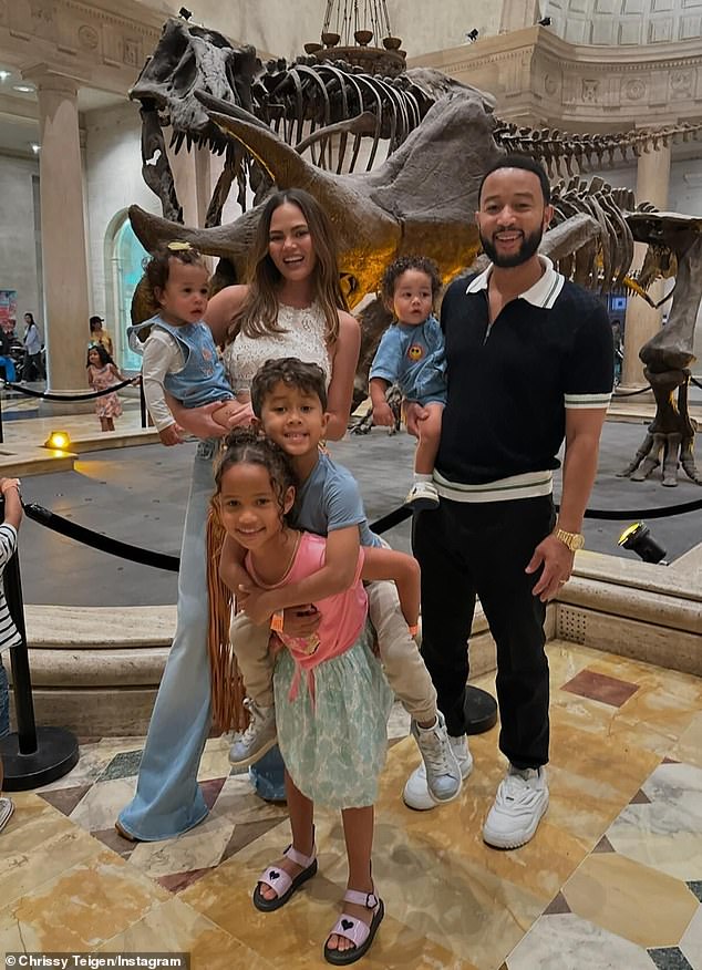 She and Legend, 45, posed for a family photo in front of the giant dinosaur skeletons with their children Luna Simone, 8, Miles Theodore, 6, Esti Maxine, 16 months, and Wren Alexander, 11 months.