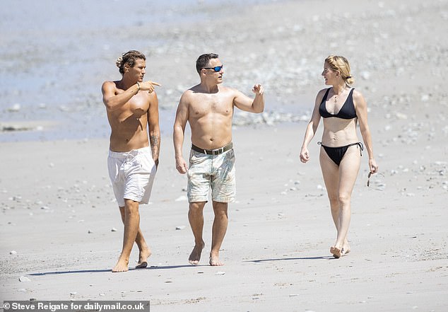 Ellie flaunted her toned figure in a black bikini with her back tied in a low bun as she smiled at Armando, who showed off his washboard abs in a white swimsuit.