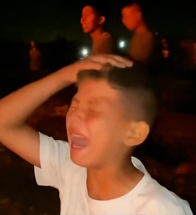 A Palestinian child is seen crying as he watches the fire ravage the displaced persons camp.