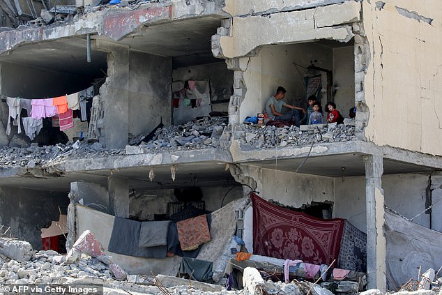 A Palestinian and his children sit in a destroyed room after the Israeli airstrike on a residential building in Rafah, a 