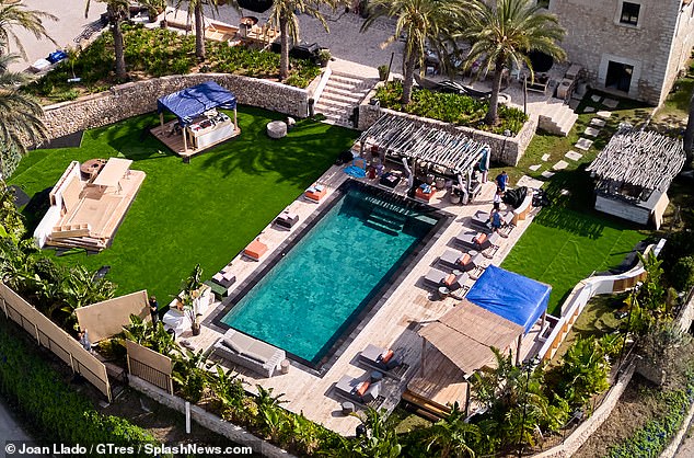 The pool area is surrounded by luxurious beds and palm trees.