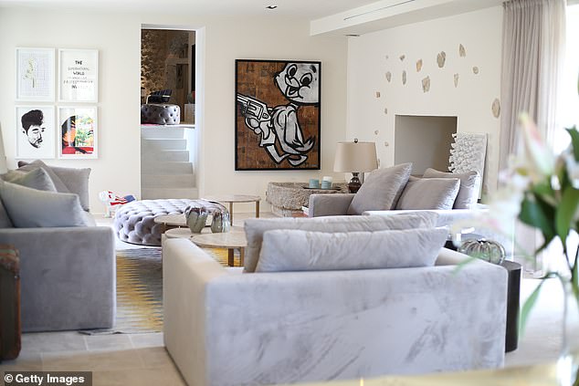 The interiors of the villa show a large living room with high ceilings and pop culture artworks on display.