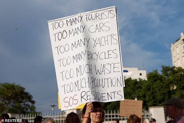 A protester holds a sign during a protest against mass tourism and gentrification.