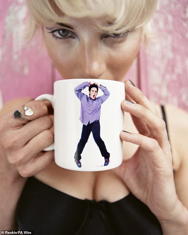 One particularly artsy photo shows busty Natasha Helms about to take a sip from a mug depicting Robbie Williams dancing.