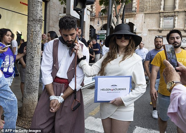 Protesters take part in a performance depicting a tourist and a Mallorcan dressed in traditional costume during a demonstration to protest against the massification of tourism and housing prices.