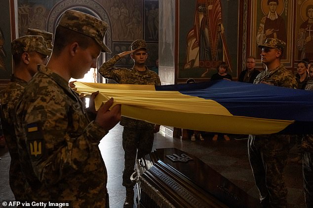 Ukrainian soldiers hold a national flag over the coffin of Ukrainian soldier Ruslan Troianchuk, with callsign "Friend"who was killed in the Donetsk region