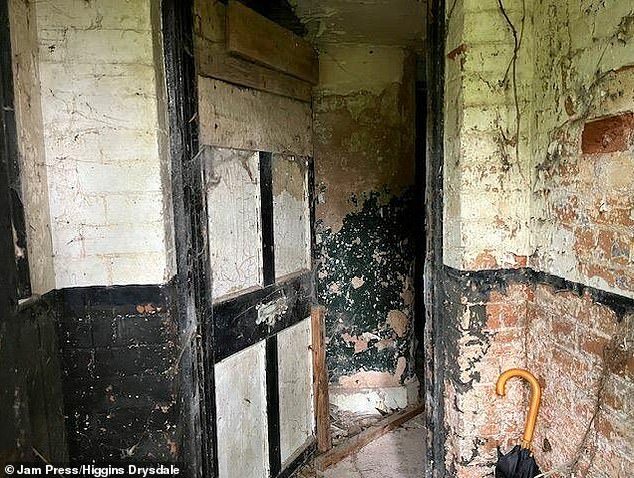 A gate to the property covered in cobwebs and peeling plaster (pictured)