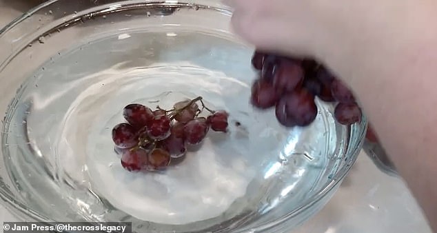 Berries and grapes are soaked in water and vinegar and stirred to clean all sides.