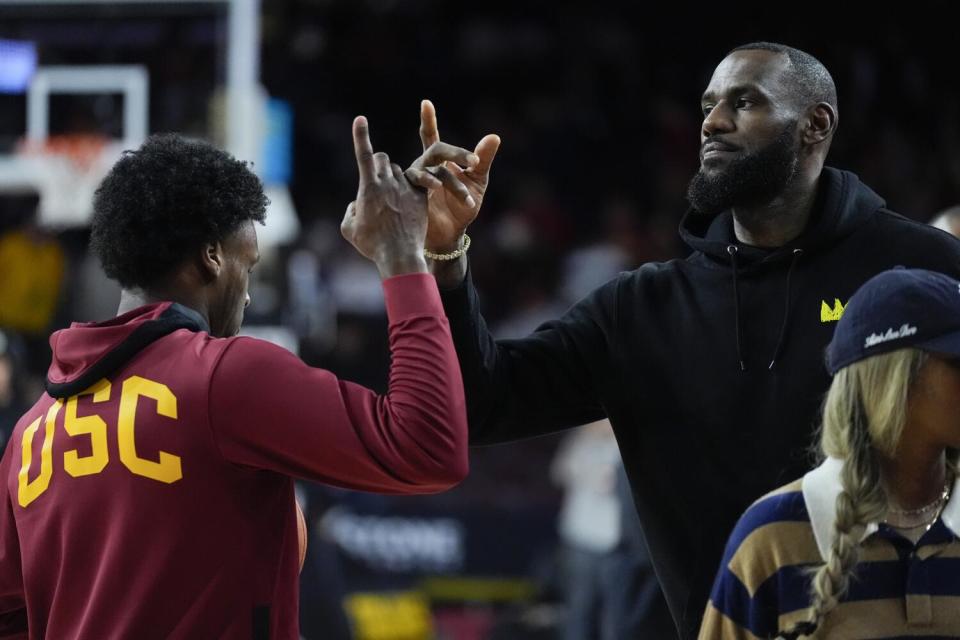 USC guard Bronny James pats his father, LeBron James, on the hand while warming up before a game.