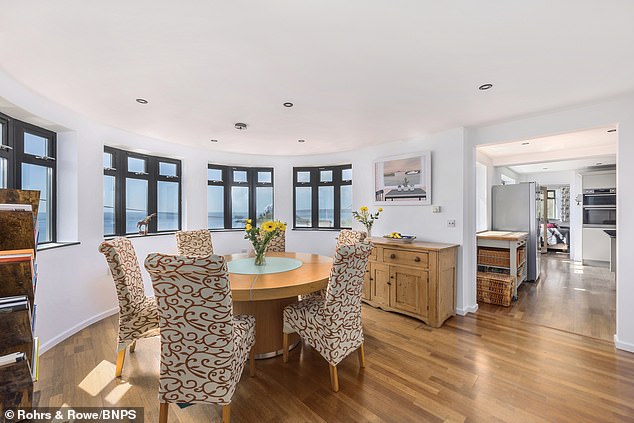 The open plan kitchen leads to a dining room with windows overlooking the coast.