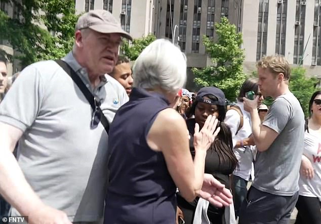 The woman's partner is seen leading her away from the commotion as protesters shout vulgar profanities at her.