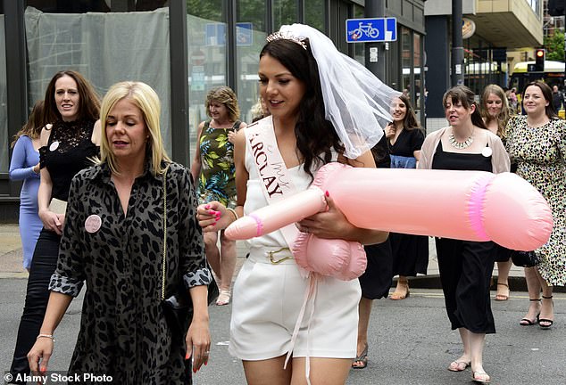 The bride at a bachelorette party is shown holding an inflatable penis.