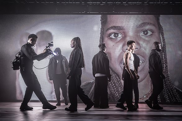 Instead, we see the stygian darkness of Soutra Gilmour's scenic design, empty except for lighting rigs and a giant movie poster broadcasting close-ups of the action as cameramen follow the actors on stage and around the building itself (the Romeo's banishment to Mantua takes him to the roof)