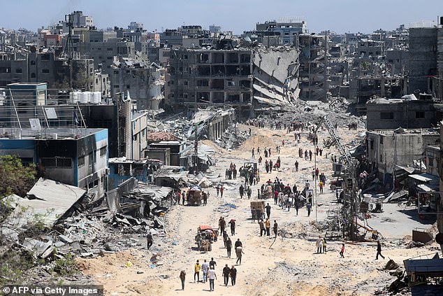 Palestinians carry some recovered belongings as they leave the Jabalia refugee camp.